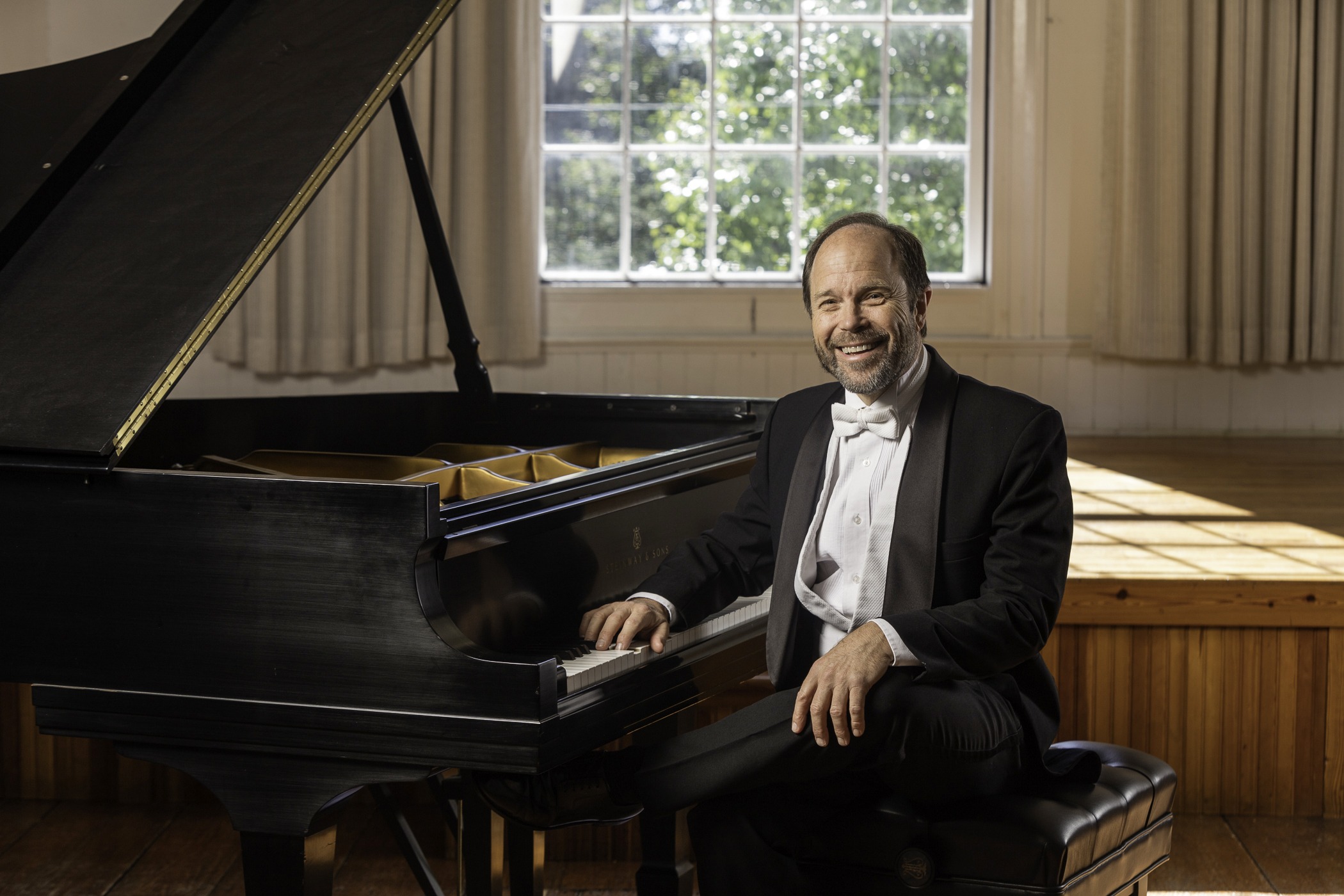 Fredrick Moyer sitting at his piano smiling