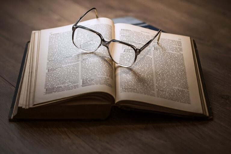 Opened novel with a pair of glasses resting on top