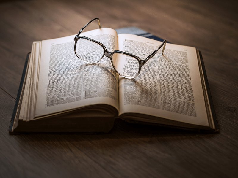 Opened novel with a pair of glasses resting on top