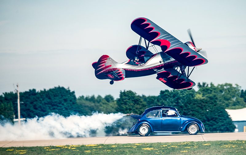 bi-plane flying over a volkswagon