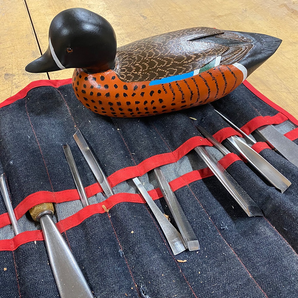 Carved wooden duck and carvers tool belt