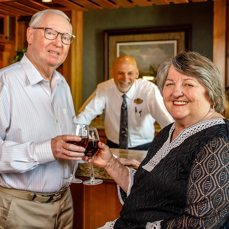 Garlands couple toasting wine glass as the bartender looks on