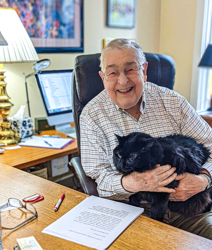 Rem at his desk writing with his pet – a black cat.