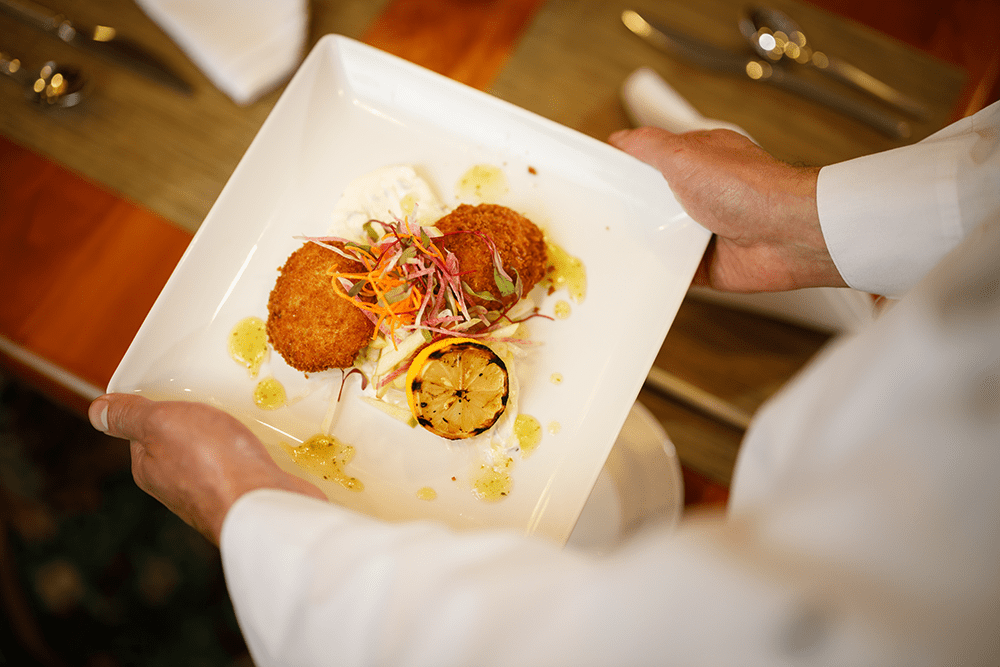 Chef setting a breaded appetizer on a table