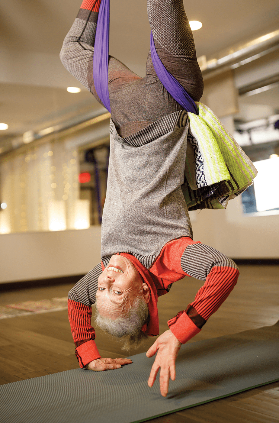 A fit Garlands resident hangs upside down in arial yoga class