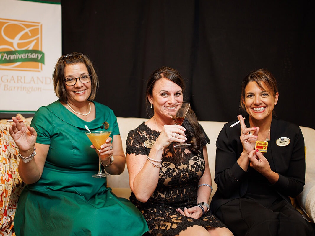 Three Staff members dressed in period piece attire and drinking cocktails