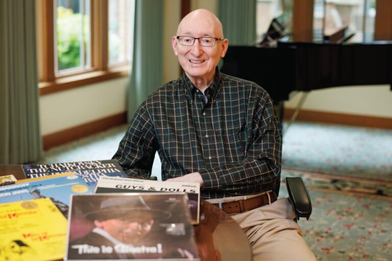 Bruce sitting in front of his piano with sheet music on the table in front of him