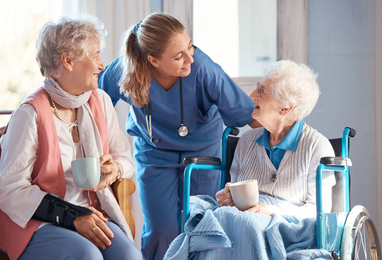 Nurse speaking to a woman in a wheelchair and her friend